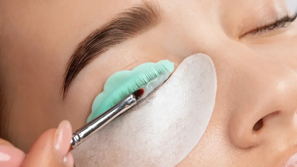 Make-up artist makes the procedure of lamination and dyeing of eyelashes to a beautiful woman in a beauty salon.